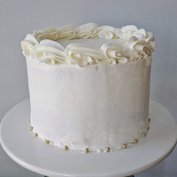 Vanilla Cake with white vanilla frosting with gold pearl decoration.