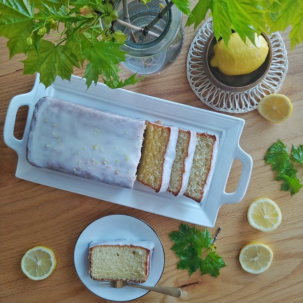 Lemon loaf on a table with fresh lemons.