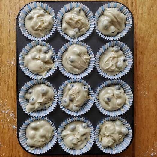 Muffin tray with scooped out batter ready for baking.