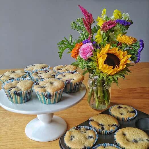 Summer flower mason jar on table with blueberry muffin display.